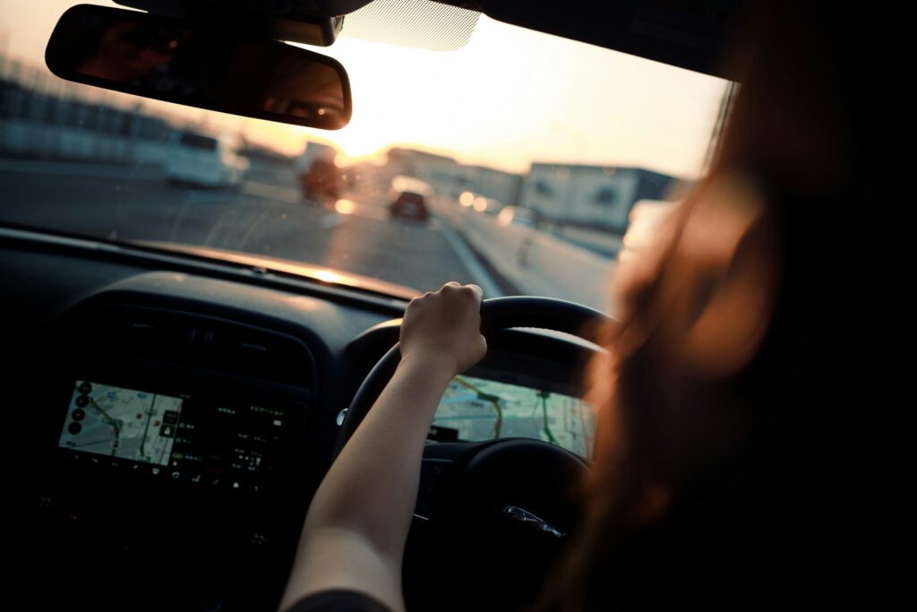 車を運転する女性。フロントガラスから前方の景色が見える。